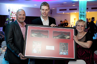 Photo of 3 people at an awards dinner holding a framed award